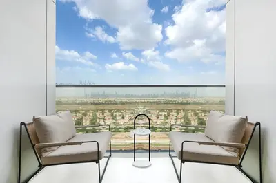 a balcony with two chairs and a view of a city at Modern 1BR Escape with Balcony View in Dubai