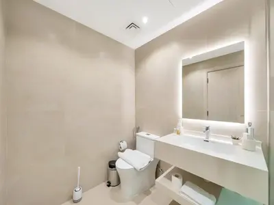 a bathroom with a sink and a toilet and a mirror at Kensington-2BR Huge & Central at Executive Tower in Dubai