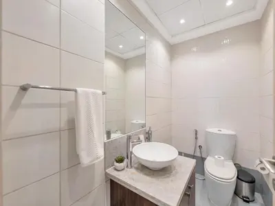a white bathroom with a sink and a toilet at Kensington-2BR Huge & Central at Executive Tower in Dubai