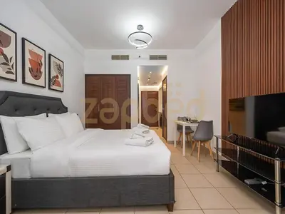 a bedroom with a white bed and a television at Zapbed Stylish Studio Boulevard Central 2 Down Town Dubai in Dubai