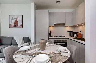 a living room with a table and a kitchen at Bright 1BR in Sobha Crest B Stunning Views & Pool in Dubai