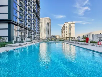 a large swimming pool in a city with tall buildings at Luxury 1BR Apartment Steps from Dubai Hills Mall in Dubai