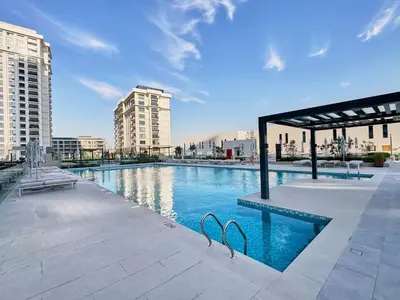 a swimming pool in a city with tall buildings at Luxury 1BR Apartment Steps from Dubai Hills Mall in Dubai
