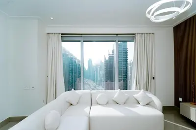 a white couch in a room with a large window at Luxury 1BR Apartment near Burj Khalifa & Dubai Mall in Dubai