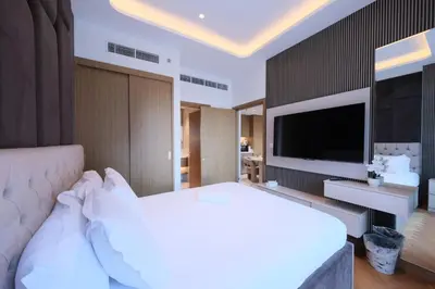 a bedroom with a large white bed and a flat screen tv at Modern 2BR Retreat Azizi Riviera 61 Square in Dubai