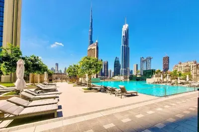 a swimming pool with lounge chairs and a city skyline at Stylish 2BHK with Burj Khalifa Views in Downtown in Dubai