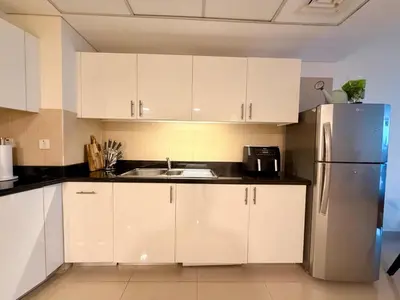 a kitchen with white cabinets and a stainless steel refrigerator at Panoramic Luxury 1BR at Park Towers, DIFC, Dubai, Stunning City View in Dubai