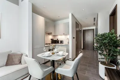 a dining room with a table and chairs and a kitchen at Elegant 1BR Sobha Crest City Views in Dubai