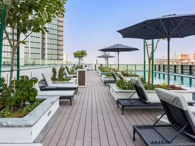 a row of chairs and umbrellas on a roof at Chic 1BR Retreat Sobha Crest with Pool & Gym in Dubai