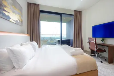 a bedroom with a large white bed with a desk and a window at Wecation - Cozy Studio , Trillionaire , Private Jacuzzi in Dubai