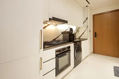 a kitchen with a stove and a washer and dryer at Wecation - Cozy Studio , Trillionaire , Private Jacuzzi in Dubai
