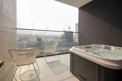 a bathroom with a tub and two chairs and a window at Wecation - Cozy Studio , Trillionaire , Private Jacuzzi in Dubai