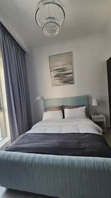 a bedroom with a blue bed with a chandelier at Bay Central 1BR with Full Marina View in Dubai
