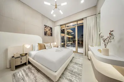 a white bedroom with a large bed and a desk at Spacious 1BR in JVC with Lounge Access in Dubai