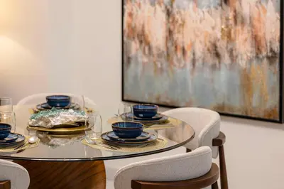a glass table with plates and cups on top at Daniels 2BR Duplex at Central Park Tower, DIFC in Dubai