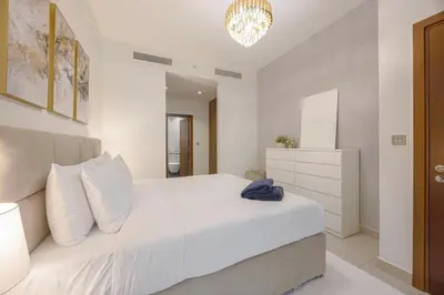 a bedroom with a white bed and a chandelier at Daniels 2BR Duplex at Central Park Tower, DIFC in Dubai
