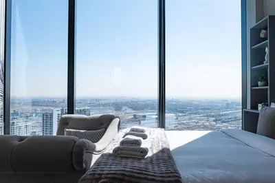 a bedroom with a bed and chairs in front of windows at The Address JBR, Address Beach Resort, Marina View - Onelink in Dubai