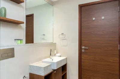 a bathroom with a sink and a wooden door at CitiHome - Spacious 2BR - Park Gate Residences in Dubai