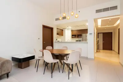 a dining room with a wooden table and white chairs at CitiHome - Spacious 2BR - Park Gate Residences in Dubai