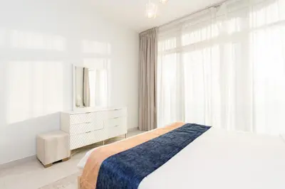 a white bedroom with a bed and a dresser and a mirror at CitiHome - Spacious 1BR - Park Gate Residences in Dubai
