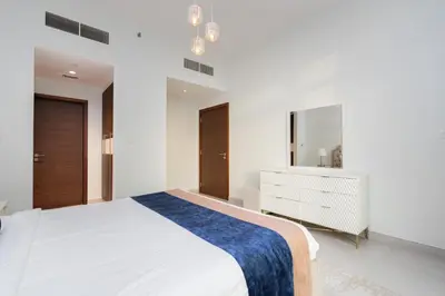 a white bedroom with a large bed and a dresser at CitiHome - Spacious 1BR - Park Gate Residences in Dubai