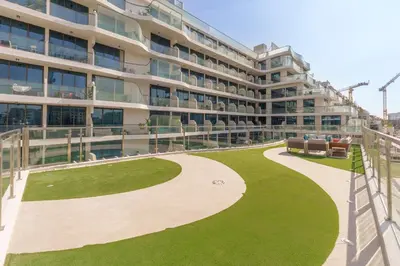 a large building with a green lawn in front of it at Luxury 2BR with Private Pool Balcony Arjan in Dubai