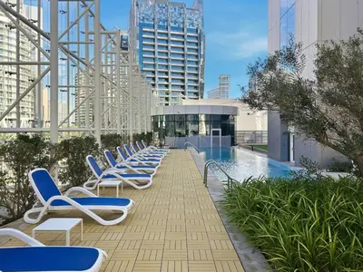 a row of blue and white lounge chairs next to a pool at Stylish Apartment Business Bay Prime Location in Dubai
