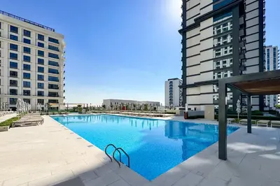 a large swimming pool in a city with tall buildings at PVH - Chic Pool View 2BR Near Dubai Hills Park - Park Field Tower 2 in Dubai