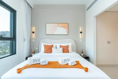 a bedroom with a large white bed with orange pillows at PVH - Chic Pool View 2BR Near Dubai Hills Park - Park Field Tower 2 in Dubai