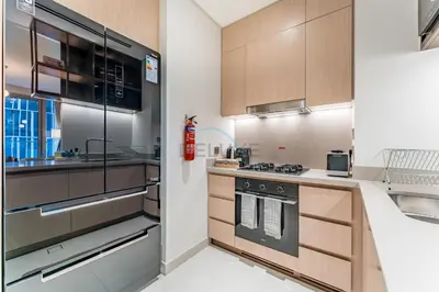 a kitchen with stainless steel appliances and wooden cabinets at Direct Walking Access to Dubai Mall and Burj Khalifa with Metro Connectivity to Prime Attractions - Vida Dubai Mall Tower 2, Downtown Dubai by Deluxe Holiday Homes in Dubai