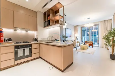a kitchen with wooden cabinets and a living room at Direct Walking Access to Dubai Mall and Burj Khalifa with Metro Connectivity to Prime Attractions - Vida Dubai Mall Tower 2, Downtown Dubai by Deluxe Holiday Homes in Dubai