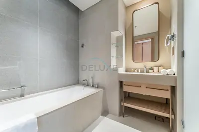 a bathroom with a tub and a sink and a mirror at Direct Walking Access to Dubai Mall and Burj Khalifa with Metro Connectivity to Prime Attractions - Vida Dubai Mall Tower 2, Downtown Dubai by Deluxe Holiday Homes in Dubai