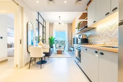 a kitchen with white cabinets and a dining room at Steps from Dubai Hills Mall, Near Scenic Park, and Easily Connected to Dubai Top Attractions - Socio Tower 1, Dubai Hills by Deluxe Holiday Homes in Dubai