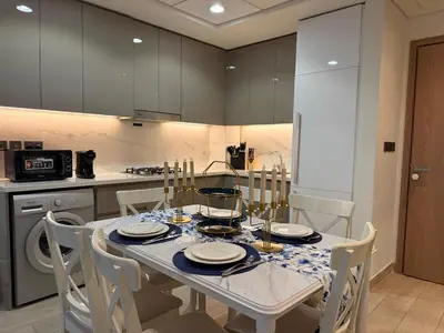 a kitchen with a table and chairs and a kitchen with a table and chairsktop at Modern 2BR with Balcony in Azizi Riviera 23 in Dubai