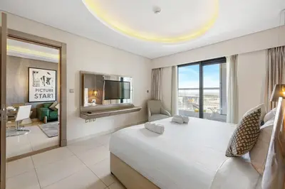 a bedroom with a large bed and a living room at Stylish 1-Bedroom Apartment at DAMAC Paramount in Dubai