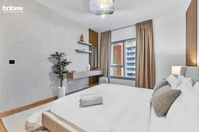a white bedroom with a white bed and a window at bnbmehomes - 29 Boulevard Tower 1 in Dubai