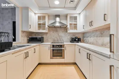 a kitchen with white cabinets and a stove top oven at bnbmehomes - 29 Boulevard Tower 1 in Dubai