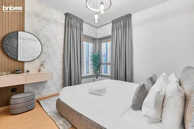 a white bedroom with a large bed and a window at bnbmehomes - 29 Boulevard Tower 1 in Dubai