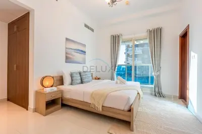 a white bedroom with a bed and a window at Family-Friendly Apartment, Few Minutes Drive to Dubai Marina, Miracle Garden and Mall of the Emirates - Elite Residences 4, Sports City by Deluxe Holiday Homes in Dubai