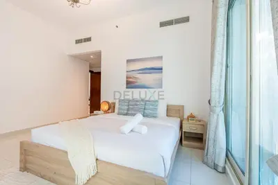 a bedroom with a white bed and a window at Family-Friendly Apartment, Few Minutes Drive to Dubai Marina, Miracle Garden and Mall of the Emirates - Elite Residences 4, Sports City by Deluxe Holiday Homes in Dubai