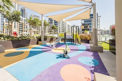 a colorful floor with a playground and an umbrella at Cozy 1BR, Easy Access to Dubai Mall - Azizi Riviera 36 by Deluxe Holiday Homes in Dubai