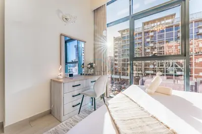 a bedroom with a bed and a desk and a window at Cozy 1BR, Easy Access to Dubai Mall - Azizi Riviera 36 by Deluxe Holiday Homes in Dubai