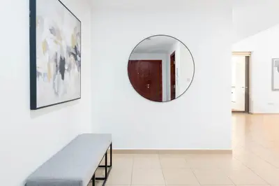 a mirror on a wall in a room with a bench at White Sage JBR Sadaf Large 1BR on High Floor with two balconies in Dubai