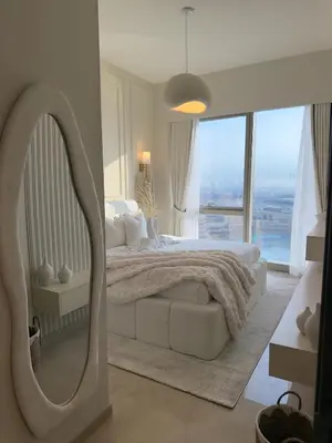 a white bedroom with a large bed and a mirror at Breathtaking 2Bedroom front-row Burj Khalifa & Fountain Views from Balcony, Grande Signature Residences in Dubai