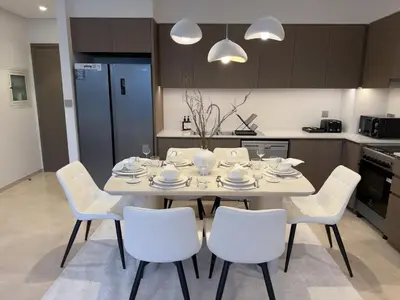 a dining room table with white chairs and a kitchen at Breathtaking 2Bedroom front-row Burj Khalifa & Fountain Views from Balcony, Grande Signature Residences in Dubai