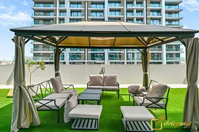 a gazebo with chairs and tables on a lawn at Luxury 2BR Dubai Hills Near Mall By Deleguest in Dubai