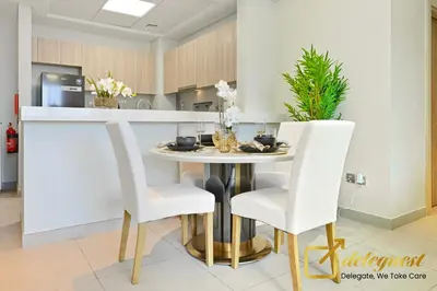 a kitchen with a table and two white chairs at Luxury 2BR Dubai Hills Near Mall By Deleguest in Dubai
