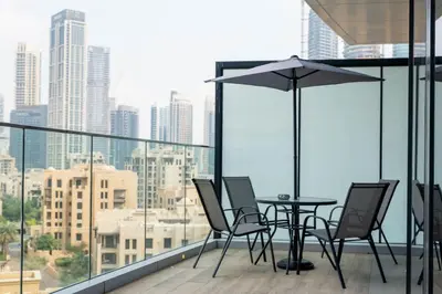 a table and chairs on a balcony with a city skyline at Iconic Burj Khalifa View - Elegant 1BR Apartment in Dubai