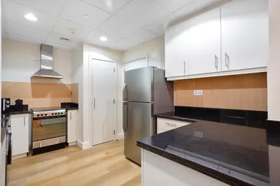 a kitchen with white cabinets and a stainless steel refrigerator at Designer 2Bedroom in Rimal near to JBR Beach in Dubai
