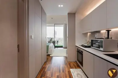 a kitchen with white cabinets and a wooden floor at Vogue JVC Binghatti Phoenix near Circle Mall, Studio Apartment with Balcony and Access to all Amenities in Dubai